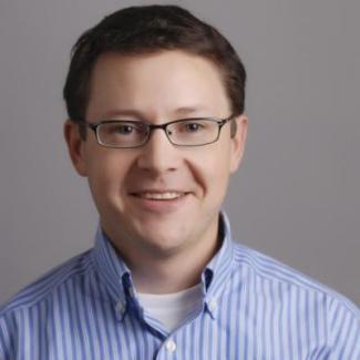 Headshot of Prof. Geoff Smith: man with brown hair and glasses, wearing a blue and white striped shirt