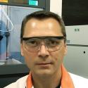 Portrait of Dr. Evgeny Alekseev, speaker. Image is of a man wearing protective eyewear with a lab in the background. 