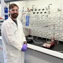 Photo of speaker Nathan Thacker standing by a fume hood in an organic chemistry lab